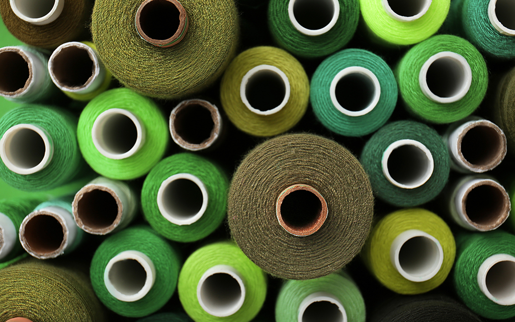 Close-up of green and olive sewing thread spools in different shades