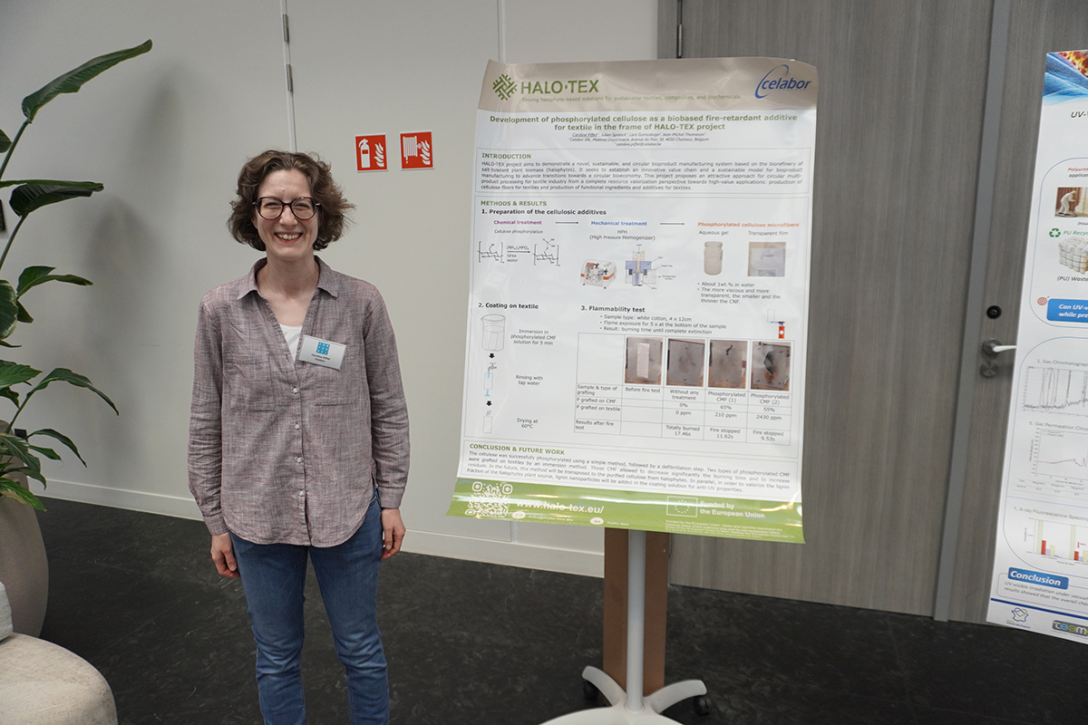 Female researcher standing next to a scientific poster presenting the HALO-TEX project's research on bio-based flame-retardant additives for textiles.